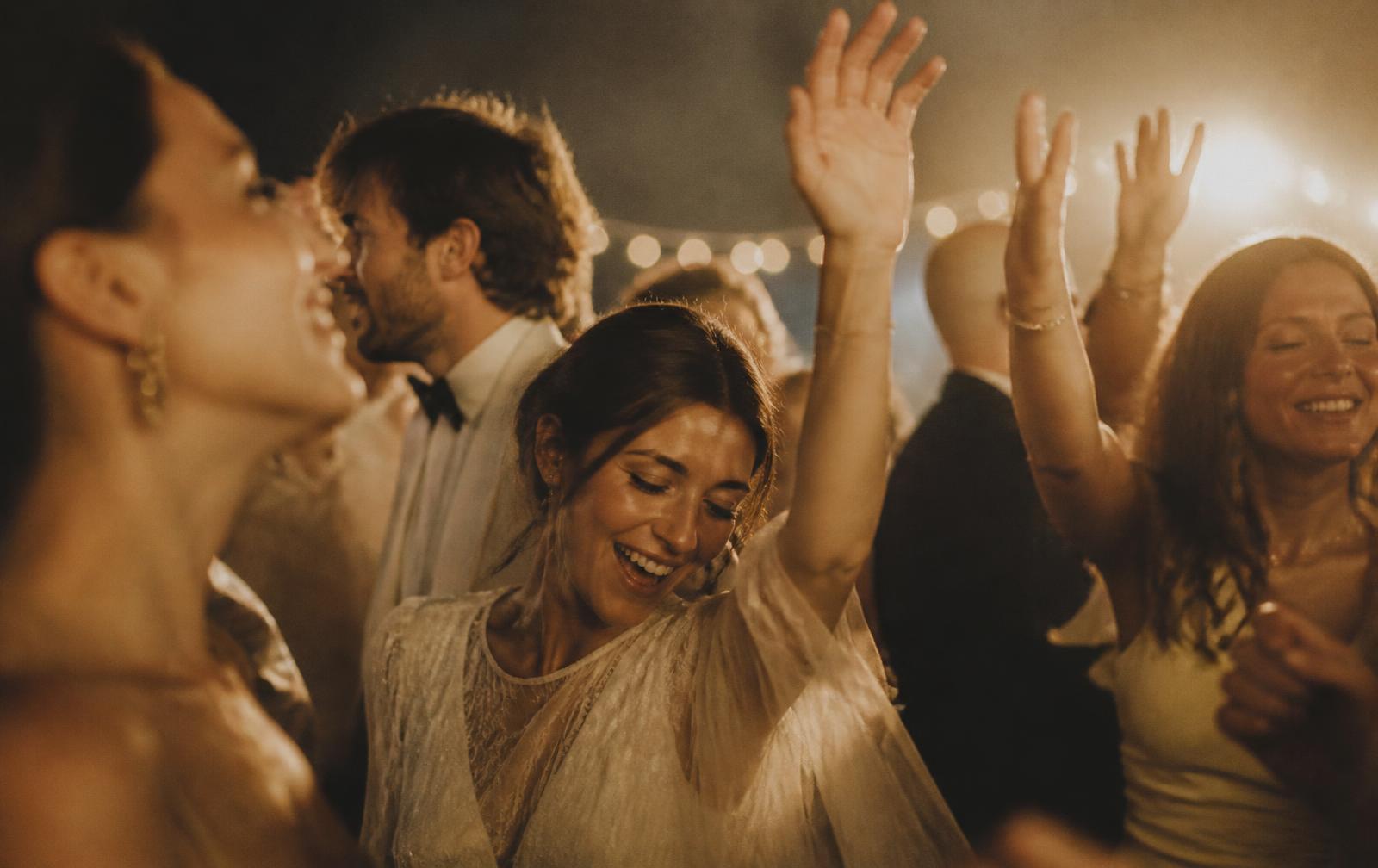 Guests dancing under festoon lights, captured candidly during a reception