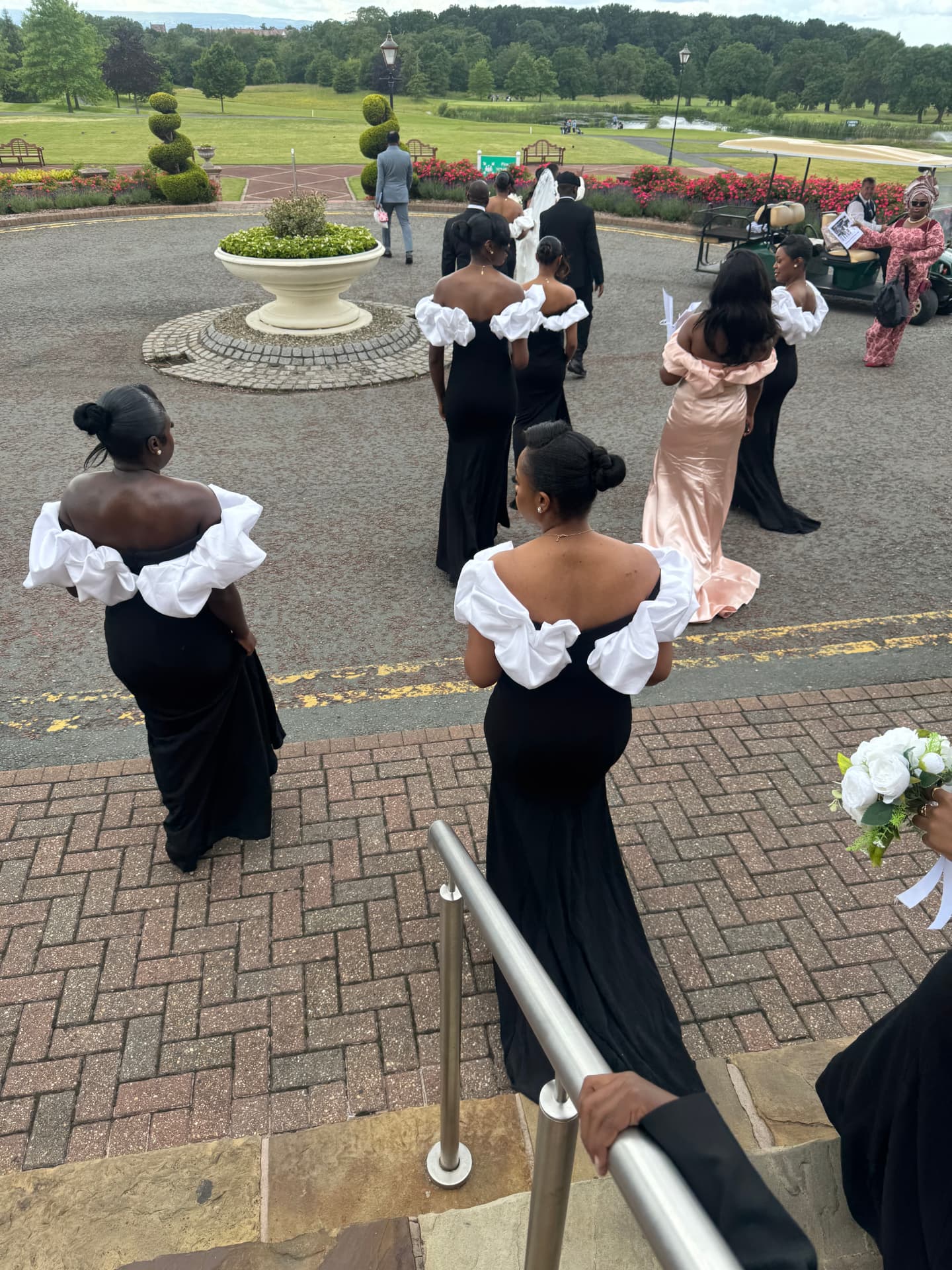 The bridal party arriving across the venue grounds in black and white dresses