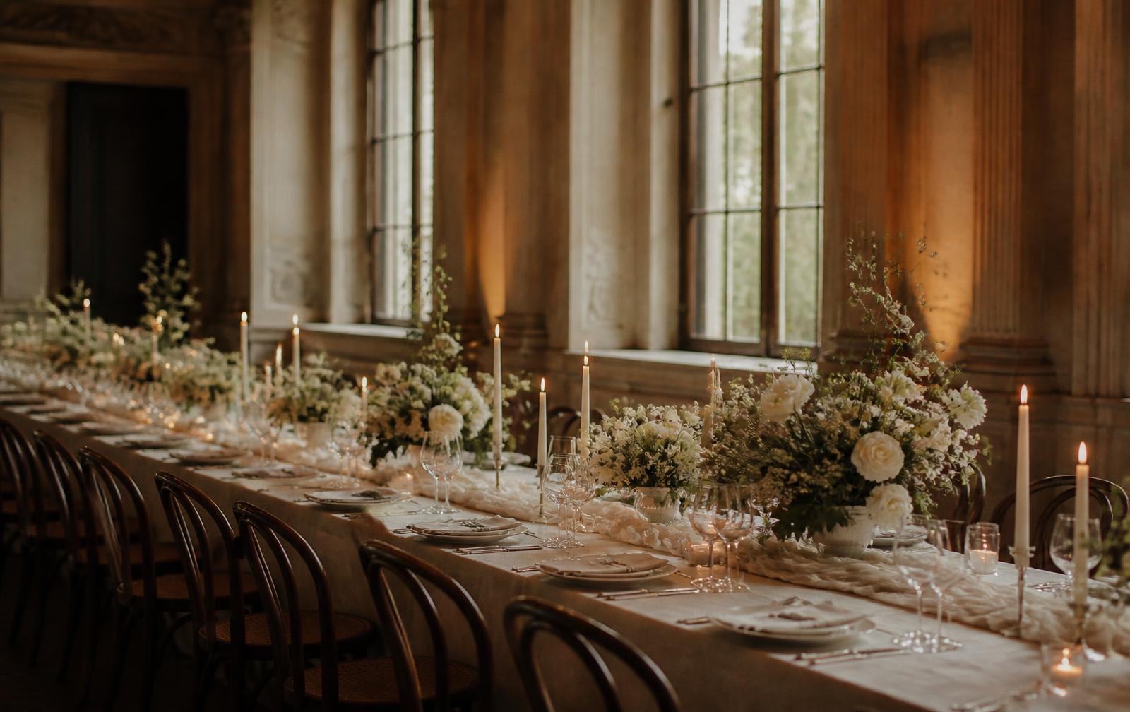 A long dressed table with candlelight and florals in a period venue